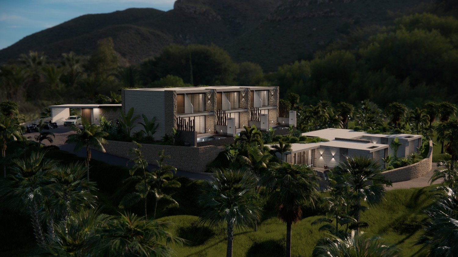 Aerial dusk view of the illuminated ALMARA estate among palms and dark hills, a lit pool below.